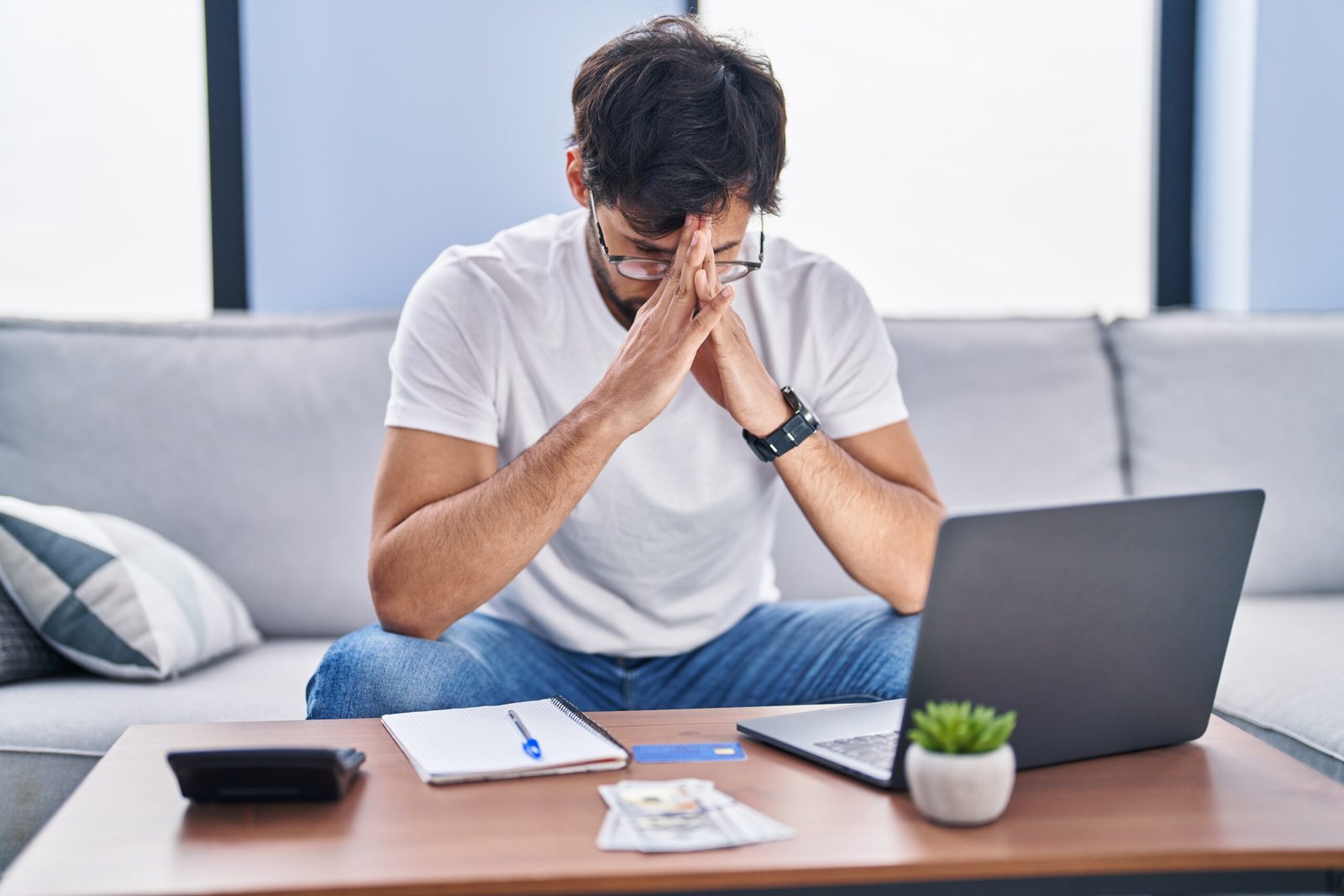 young hispanic man stressed using laptop working at home